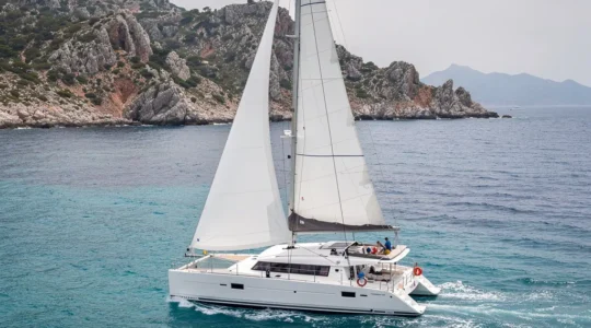 Catamaran blanc naviguant en Méditerranée avec côtes corses en arrière-plan