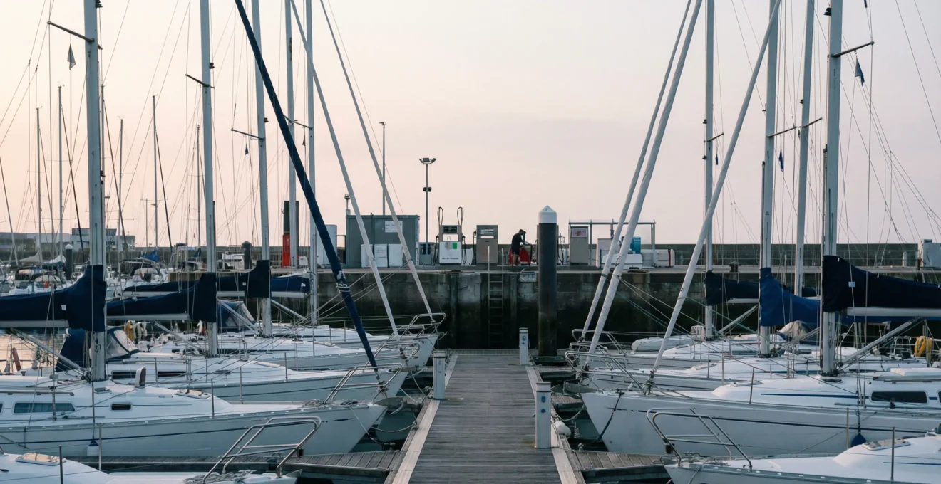 Port de plaisance français à l'aube avec bateaux amarrés et zone technique visible pour ravitaillement carburant